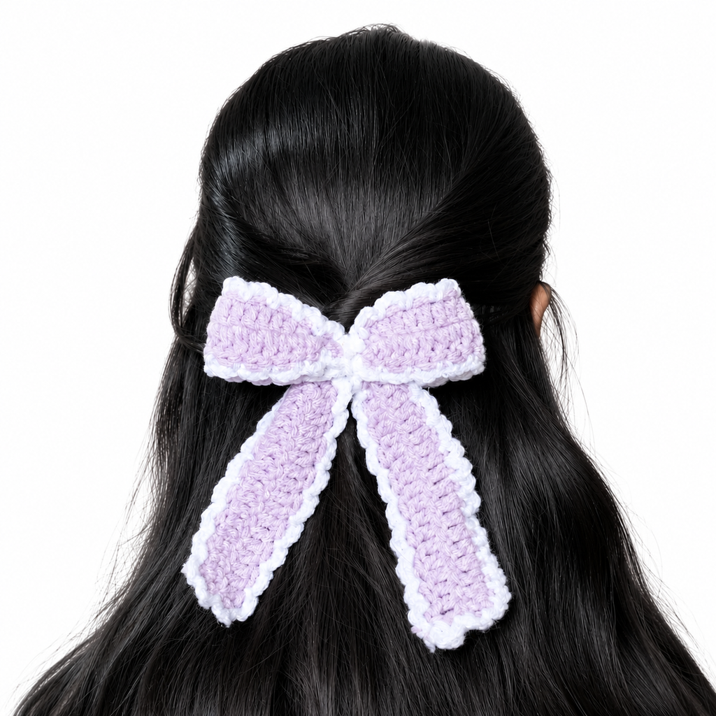 Handmade lavender and white crochet bow hair clip attached to long black hair on a white background.