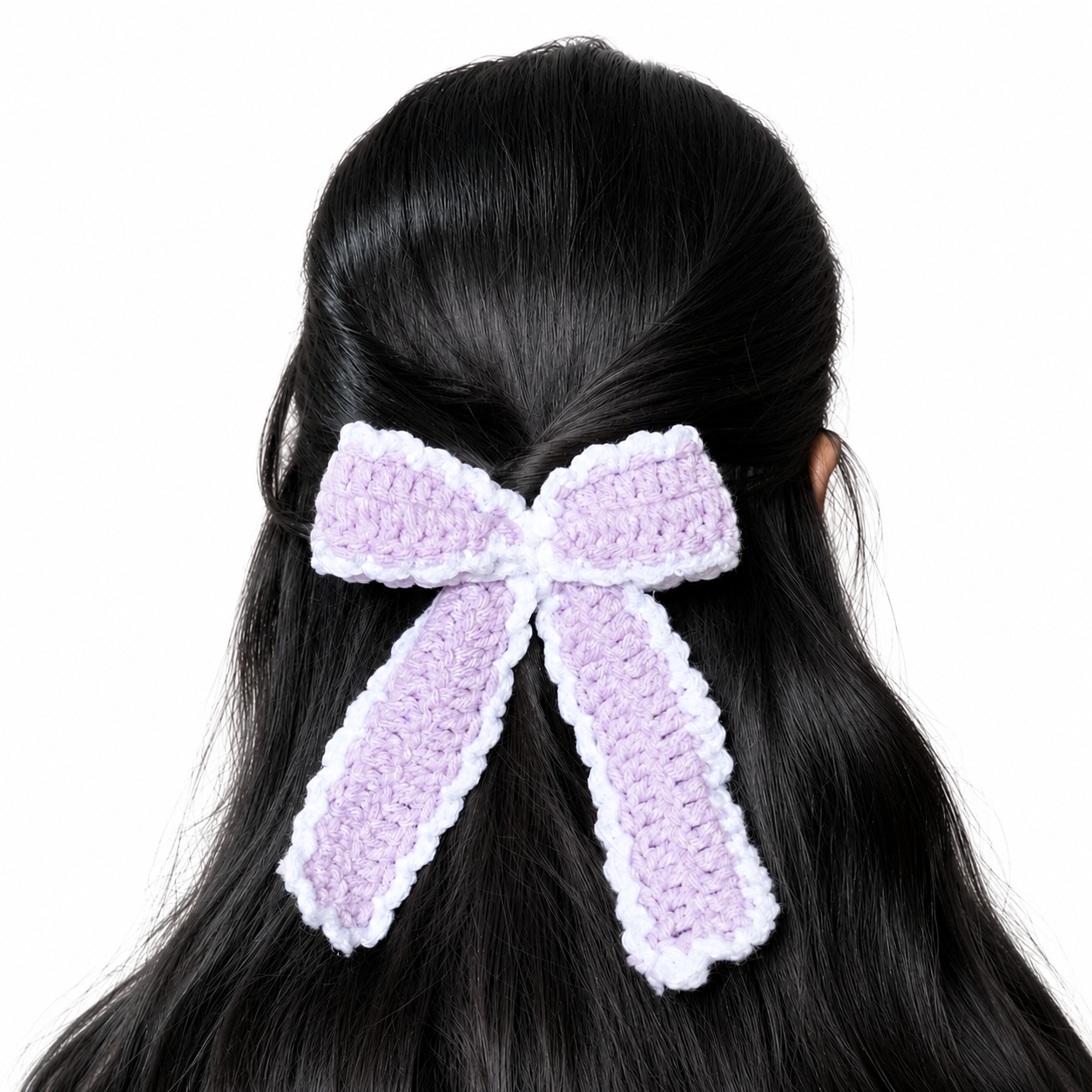 Handmade lavender and white crochet bow hair clip attached to long black hair on a white background.